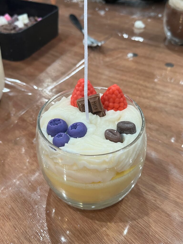 Zelfgemaakte kaars in de vorm van een dessert met frambozen, koffiebonen en blauwe bessen.